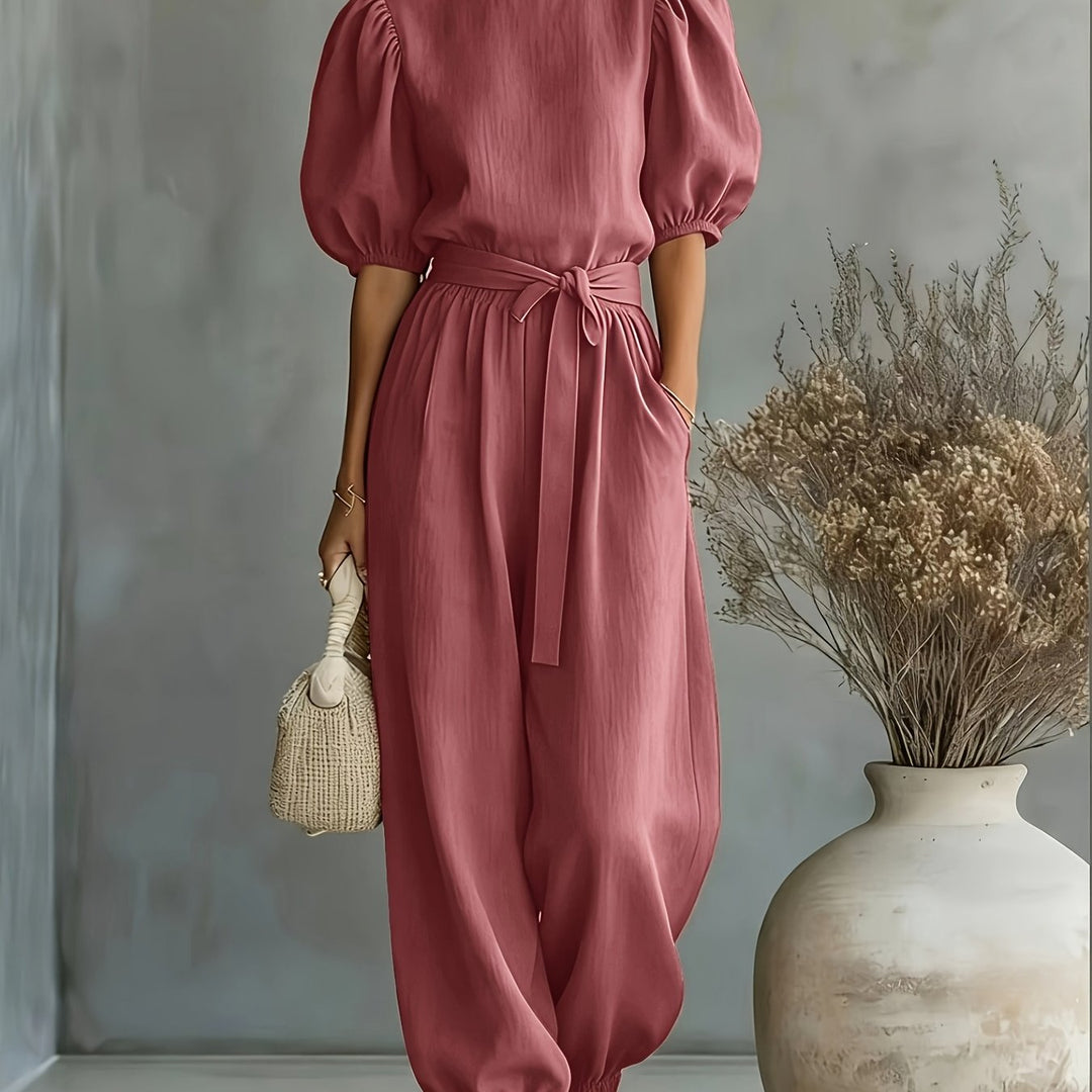 Jumpsuit i boheme-stil med pufærmer og bindebånd i taljen. Har sidelommer for bekvemmelighed, pasform og behagelig afslappet brug.