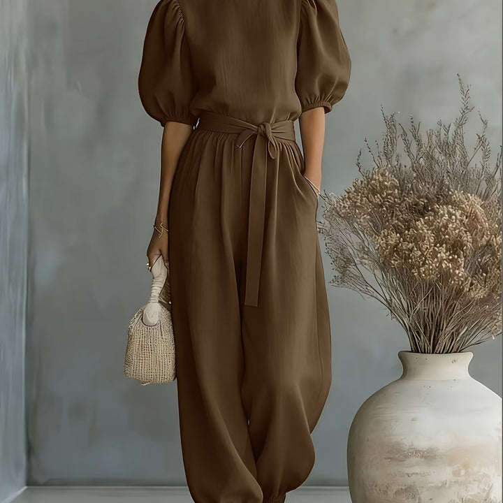 Jumpsuit i boheme-stil med pufærmer og bindebånd i taljen. Har sidelommer for bekvemmelighed, pasform og behagelig afslappet brug.